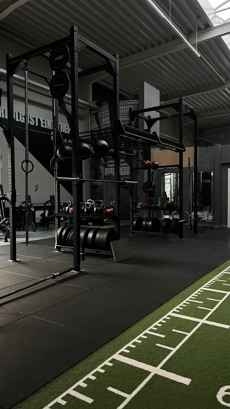 Sala de fuerza con rack y suelo de césped artificial marcado.